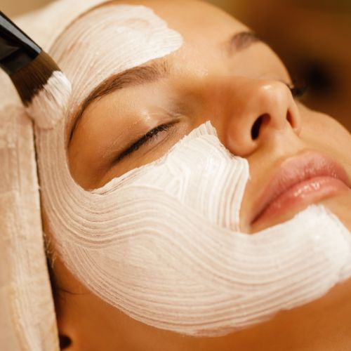 Kosmetische Gesichtsbehandlung: einer Frau wird mit einem Pinsel eine Maske aufgetragen
